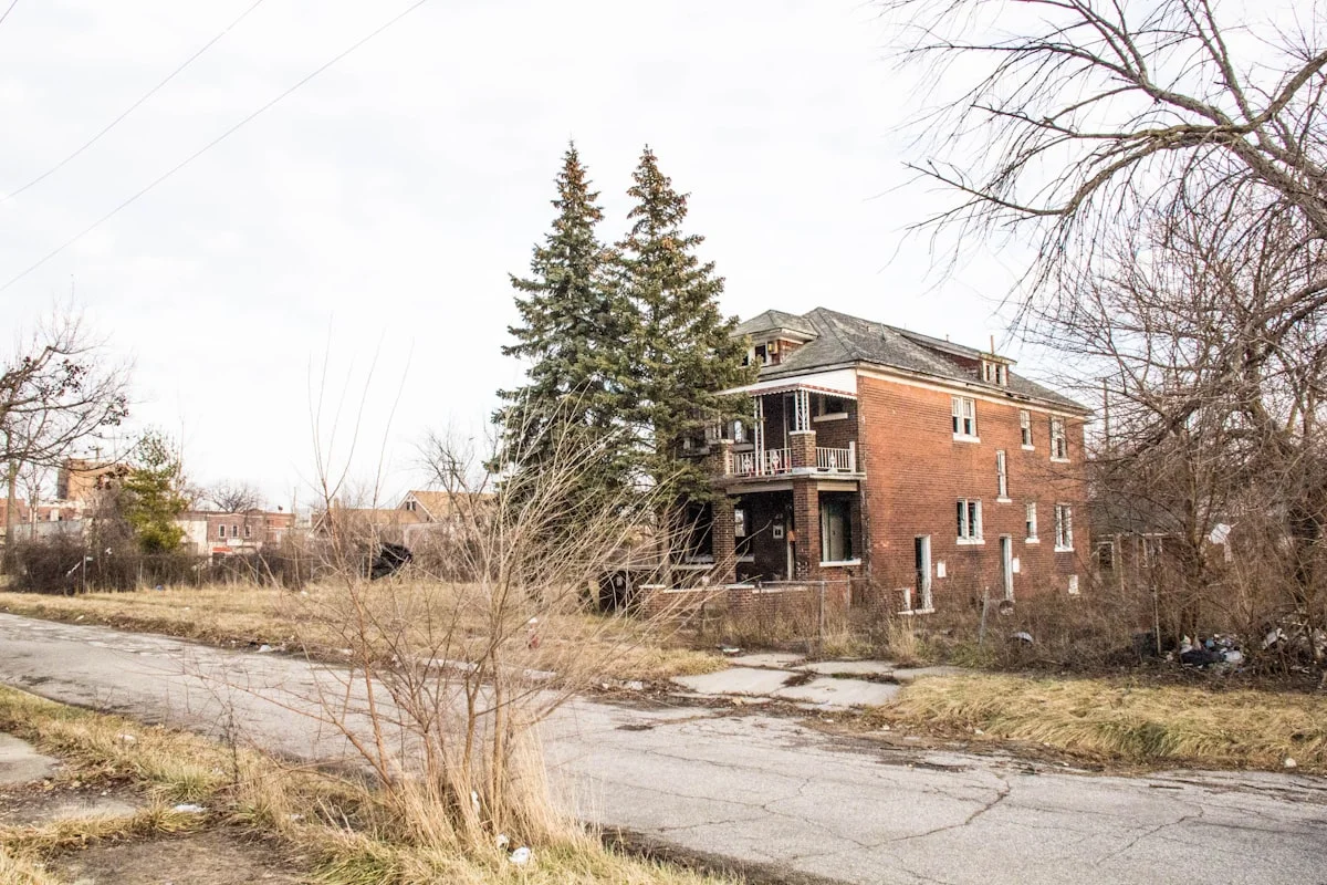 Abandoned brick building surrounded by overgrown vegetation and bare trees in New Jersey
